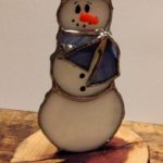 Snowman with scarf and hat on cedar