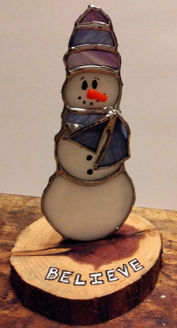 Snowman with scarf and hat on cedar